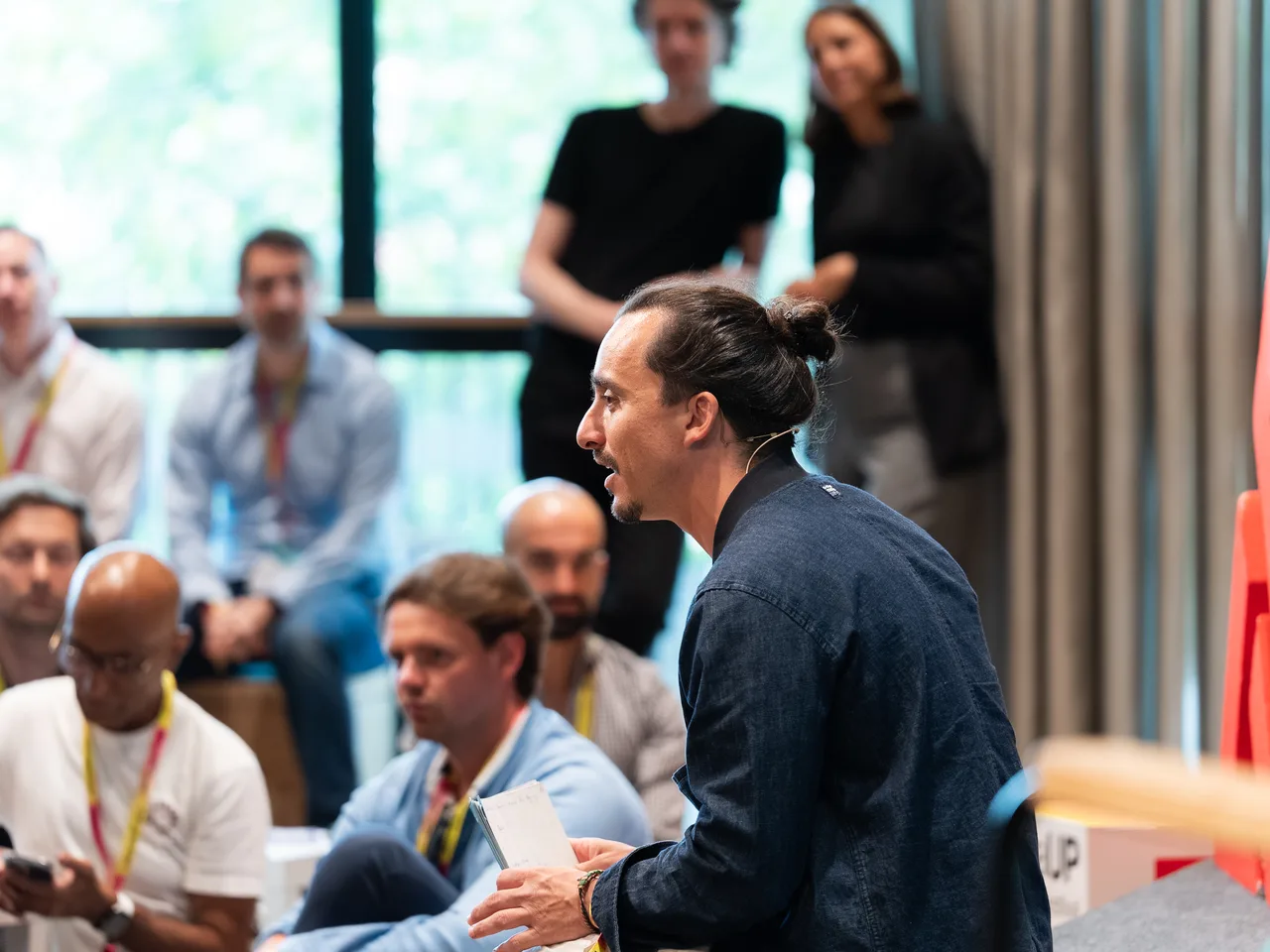 James Langer in conversation with event participants, holding notes and gesturing