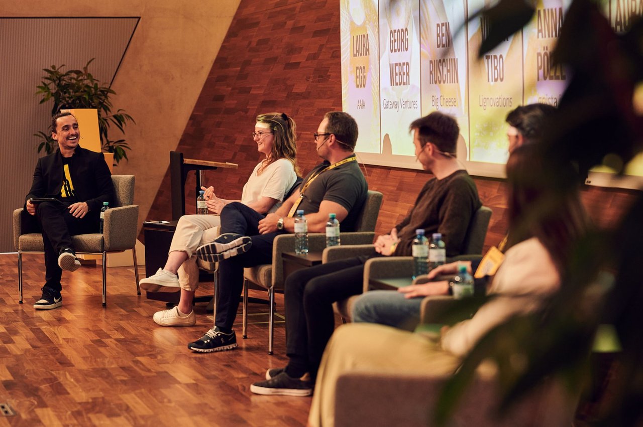 James Langer moderating a founder panel discussion on stage in front of an audience